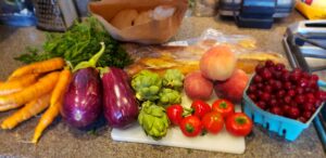 A spread of farmers market fruits and vegetables on a kitchen countertop.